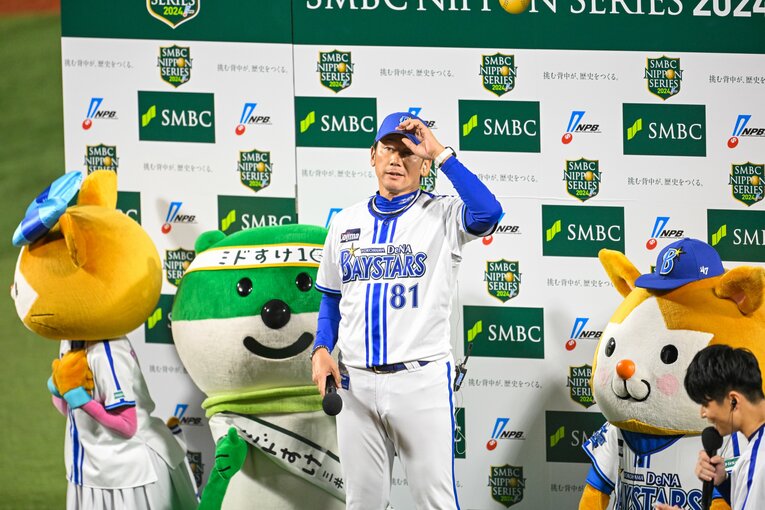 日本シリーズのスポンサーであるSMBCのパネルの前でインタビューに答えるベイスターズの三浦大輔監督　©︎Nanae Suzuki