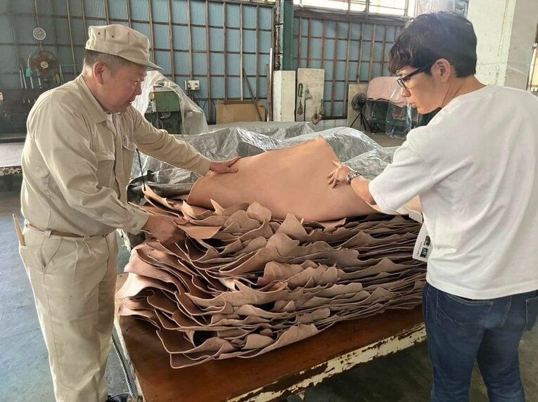 グローブに使う皮を見る健介さん／本人提供