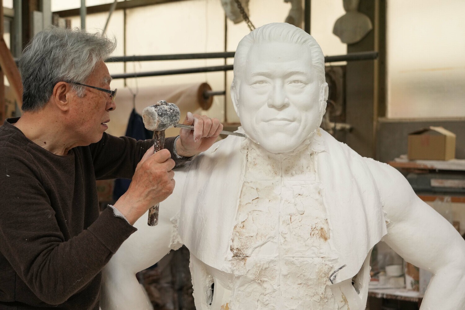 5月22日、石膏の猪木像の周りを槌で砕いていく井野雅文さん