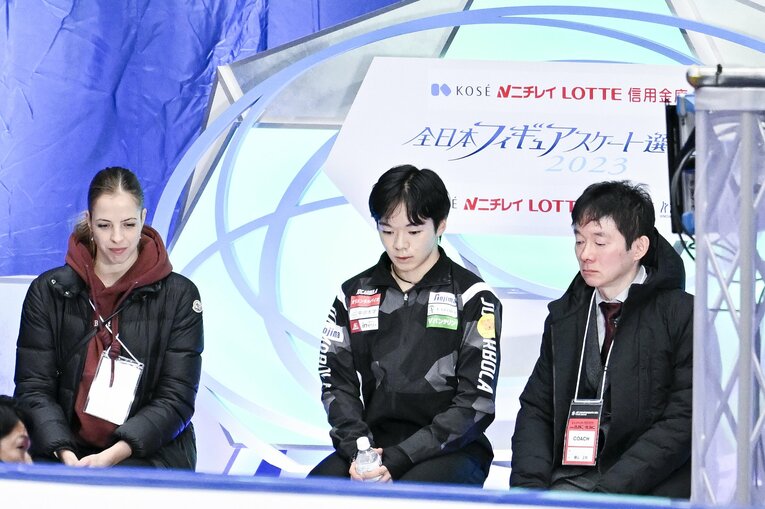 ショートの演技後、得点がのびずうつむく鍵山優真。（左）コストナーコーチ、（右）鍵山正和こーコーチ　©︎Asami Enomoto