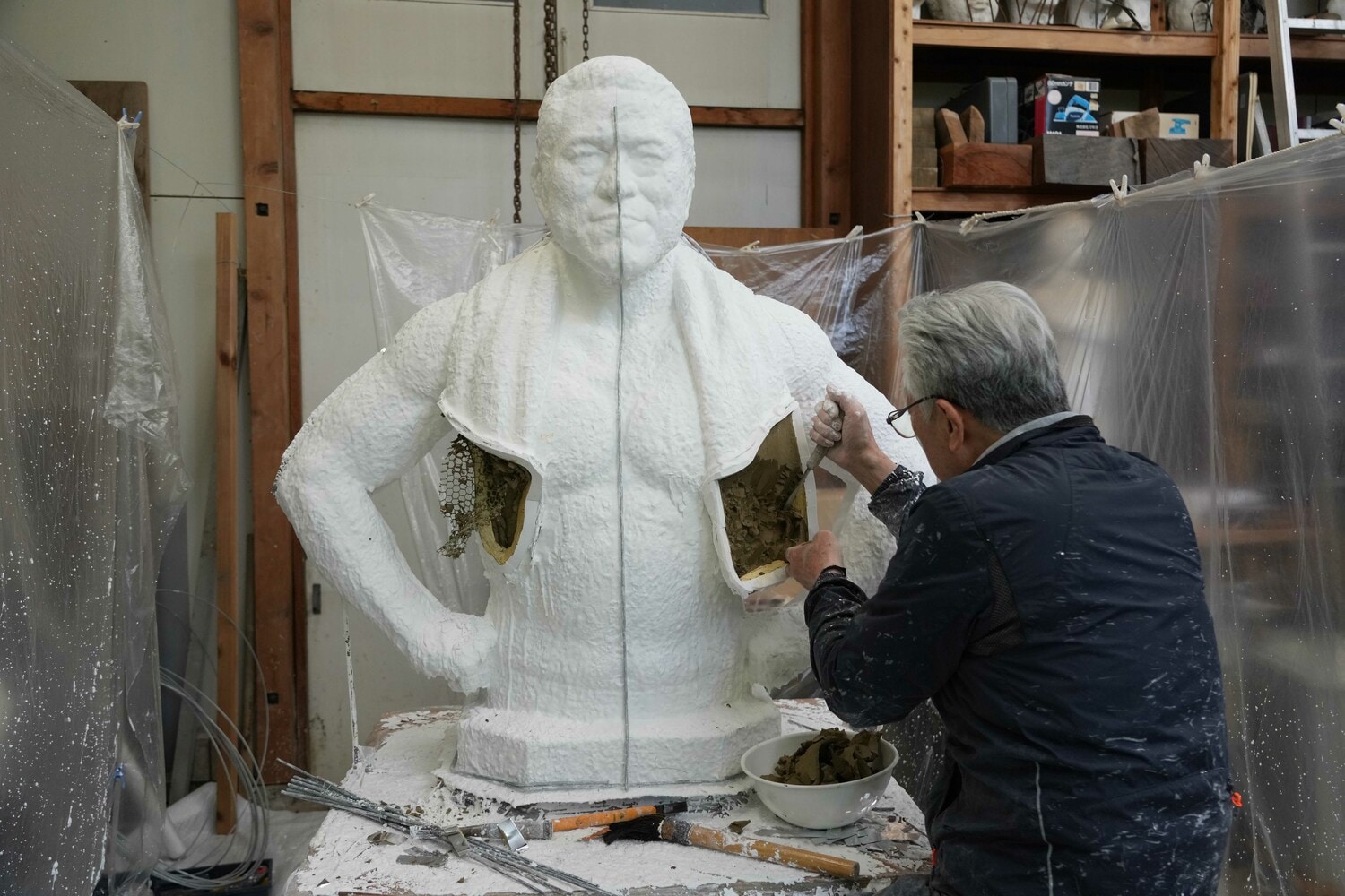 5月12日、切り離したマフラーの部分から粘土をかきだす井野雅文さん