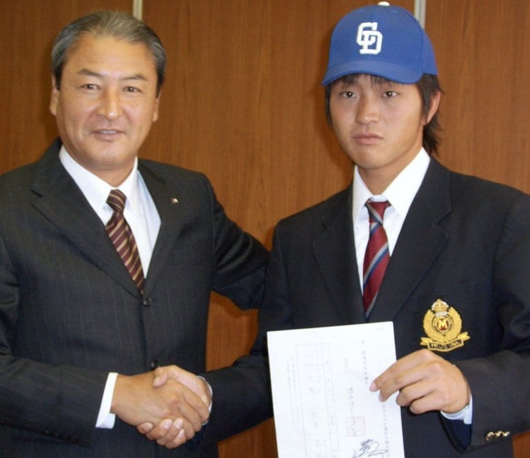 2007年ドラ1指名の山内壮馬投手（名城大）と握手する中田宗男スカウト部長（当時）。山内が手にするのは落合のサインが入ったドラフト指名用紙　©KYODO