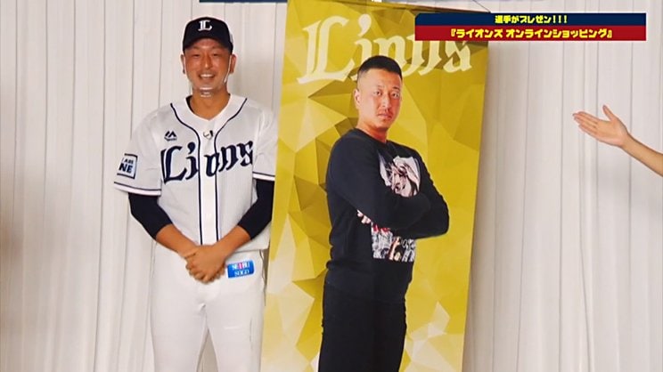 「麺や哲」「防犯グッズ」などと評された宮川さんの全身タペストリー。司会のおねーさんは事前に商品を見ていたようで、お披露目の前から笑っちゃってました　『ライオンズオンラインフェスタ 2020』より