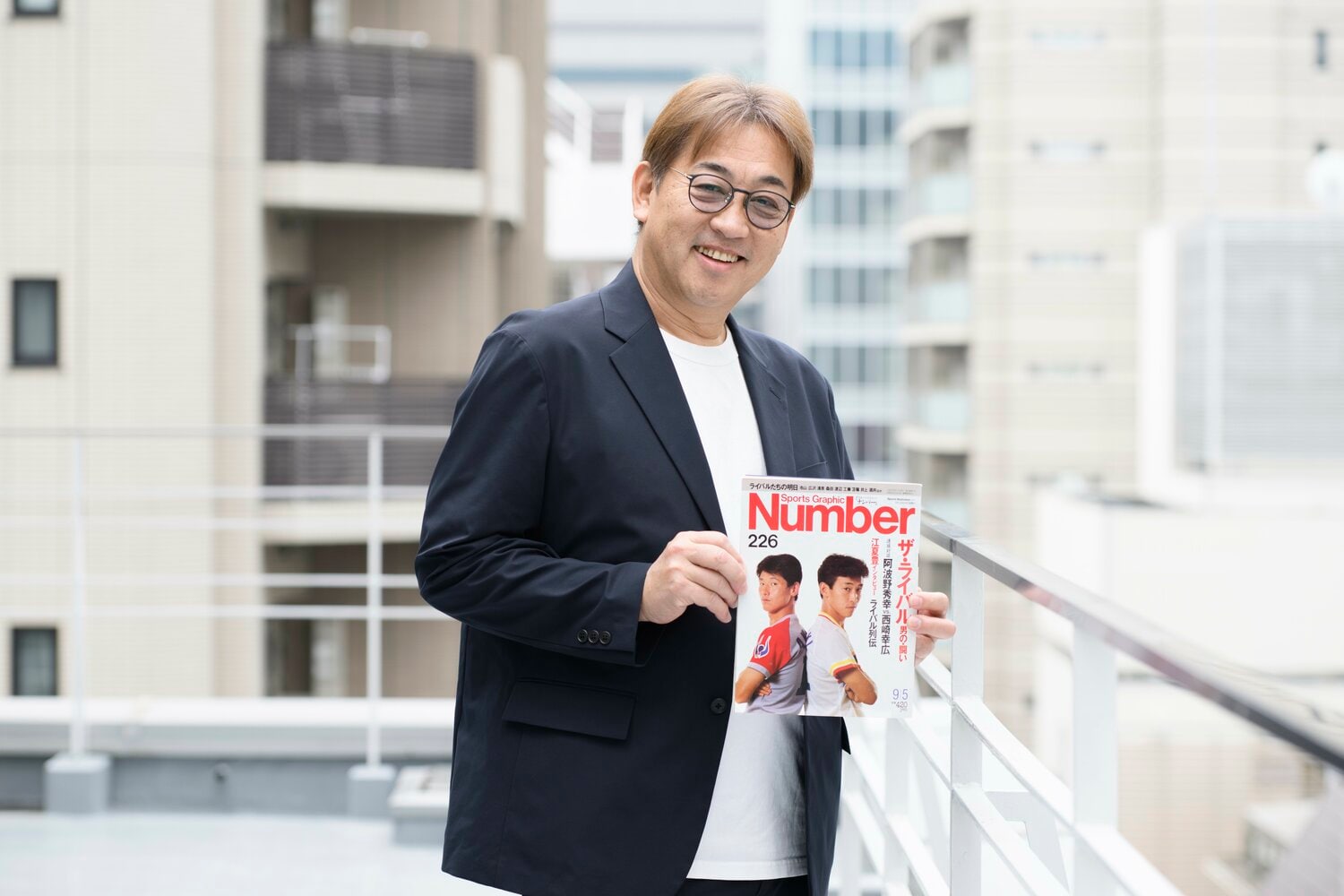 当時彼らを「ザ・ライバル」として特集したNumber誌を手にする西崎氏。ふたりの娘さん同士で同じポーズの写真を撮ったこともあるとか！　©Hirofumi Kamaya