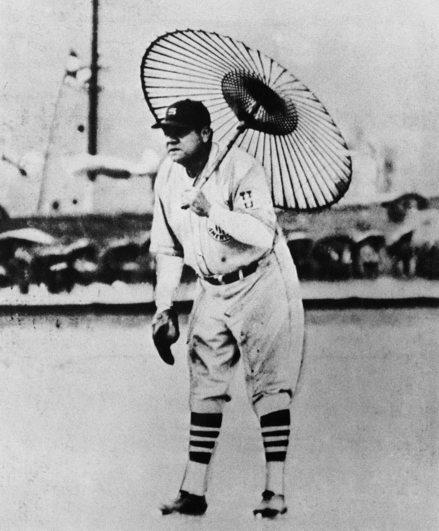 雨が降るなか、試合前練習で観客から借りた唐傘をさして一塁の守備につくベーブ・ルース　©Getty Images