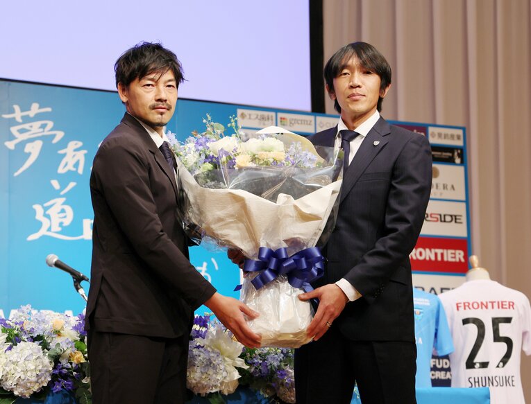 会場にサプライズで駆けつけた松井大輔（左）から花束を受け取る中村俊輔　©︎JIJI PRESS