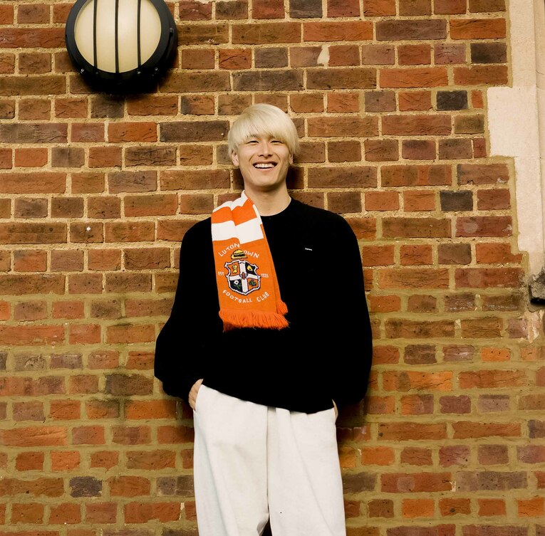 サポーターからもらったマフラーを身につけて写真撮影に応じる橋岡大樹　©︎Yudai Emmei