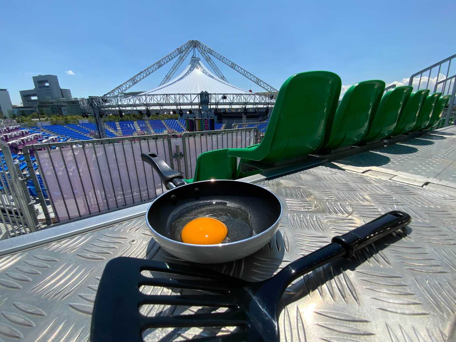 この日の最高気温は34.2℃。無観客実施で使用予定のないスタンドがとんでもない熱さだ。そこで、スタンド床の鉄板にフライパン（しっかりフライパン返しも用意）を設置。目玉焼きチャレンジを試みた
