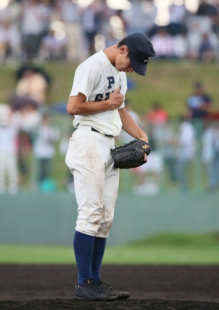 ユニフォームの下にぶら下げたアミュレット（御守り）をギュッと握りしめ、祈りを捧げるPLナイン ©JIJI PRESS