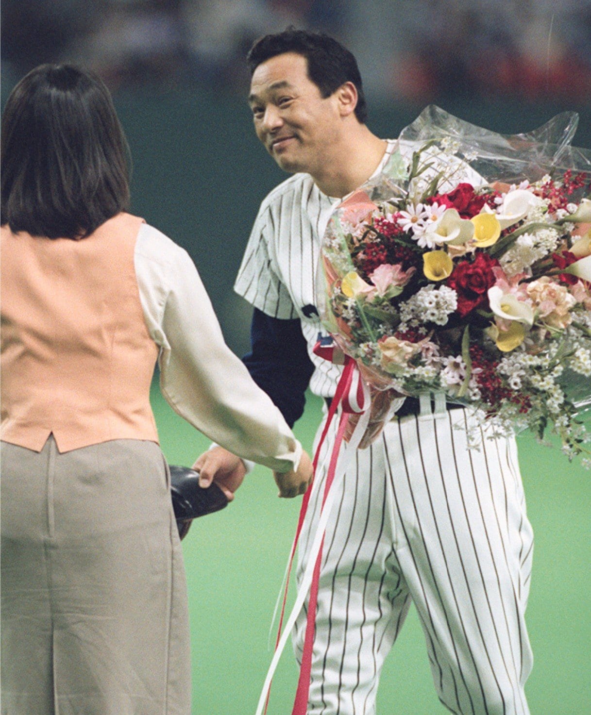 1997年5月28日ダイエー戦、セ・パ両リーグ1000安打を達成。花束で祝福を受ける落合　©KYODO
