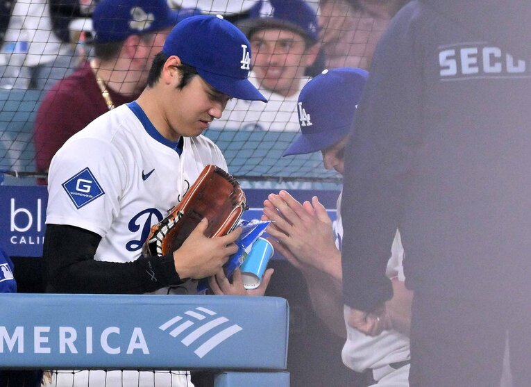 【テレビに映らないドジャース名場面】大差がついた試合で、9回から大谷（左）のグラブを使用し投手として登板した内野手のロハス。大谷にグラブを返却する際に手を合わせて感謝（写真は右に続きます）　©JIJI PRESS