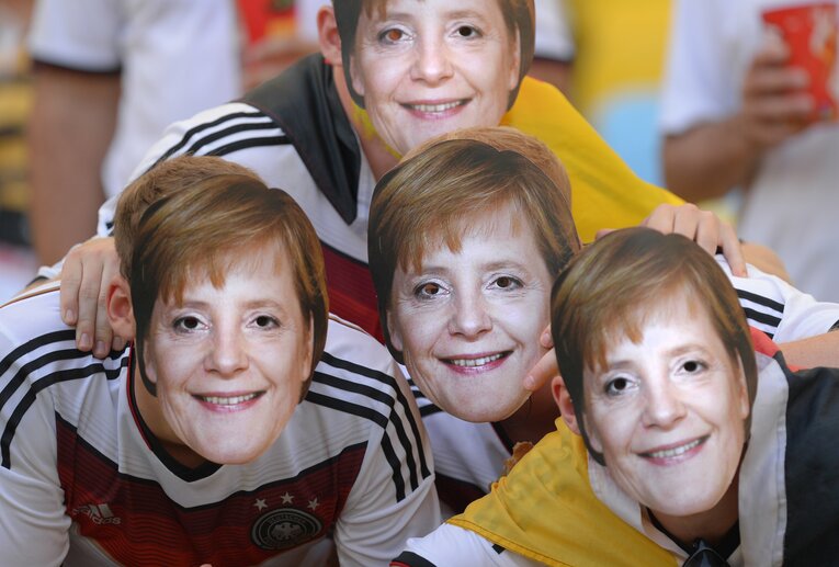 メルケル元首相のお面を被って応援するドイツ人サポーター　©︎Getty Images