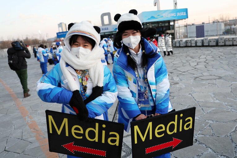「Media」と書かれた案内板をもって誘導係をするボランティアスタッフ　©Getty Images