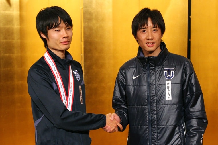 翌2012年に総合優勝を達成して握手する酒井監督（右）と“山の神”柏原竜二（c）AFLO SPORT