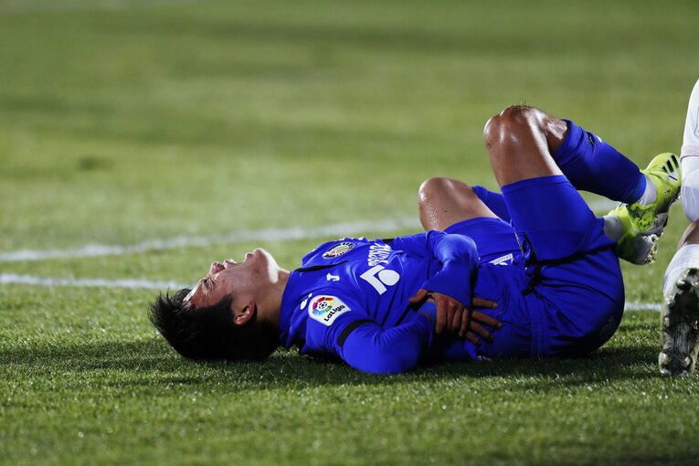 クロスに対して飛び込んで相手ともつれ合い、痛みをこらえる