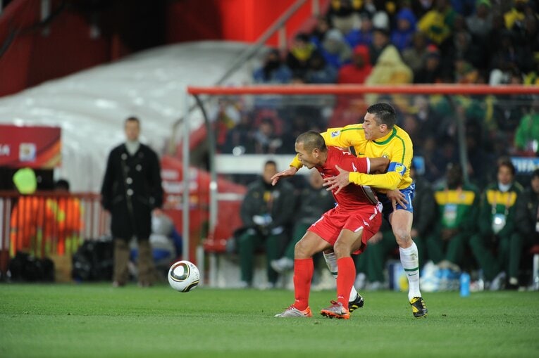 2010年南アフリカW杯。ブラジル戦でルシオを背負ってボールをキープする鄭大世　©JMPA