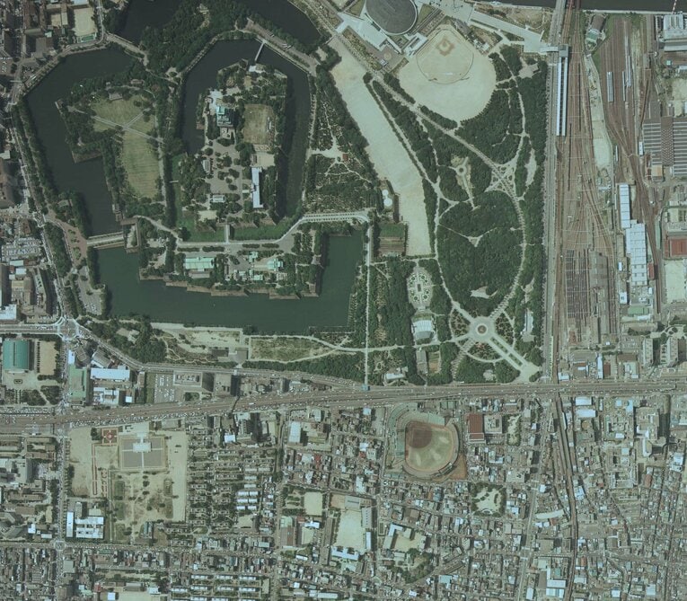 こちらは、1985年の森ノ宮駅、大阪城（左上）付近の航空写真。中央大通沿い、大阪城公園の向かいに日生球場が確認できる。森ノ宮駅は右下。右上には車両基地も見える　出典：国土地理院の空中写真