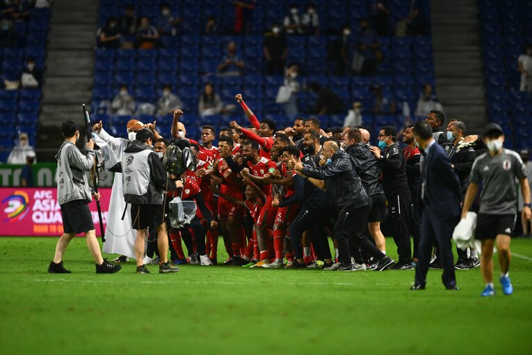 アウェイでの勝ち点3獲得に歓喜するオマーン代表はピッチで記念撮影　©JMPA