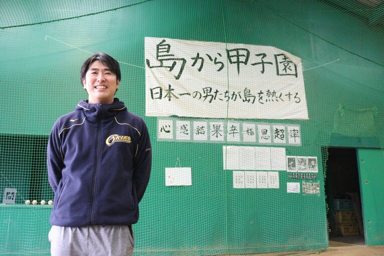 隠岐高・渡部謙監督。室内練習場には「島から甲子園」の文字。2003年以来の出場を目指す　©Yuki Kashimoto