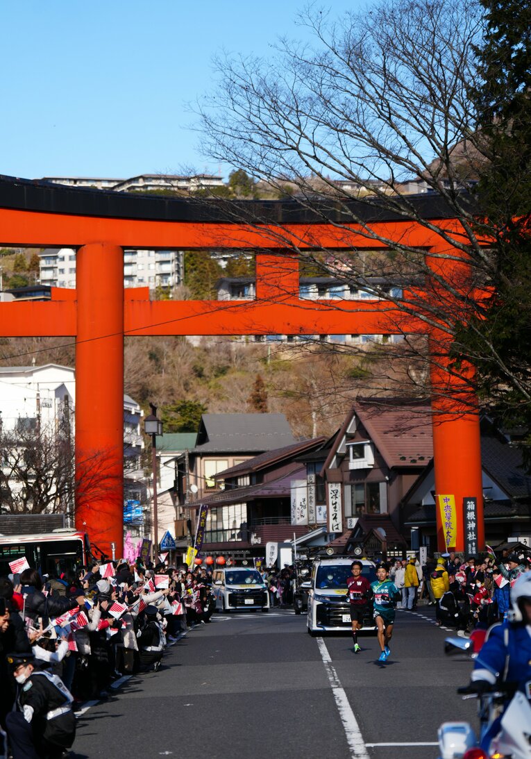 ５区、鳥居をバックに力走する早大の工藤慎作と青学大の黒田朝日　©JIJI PRESS