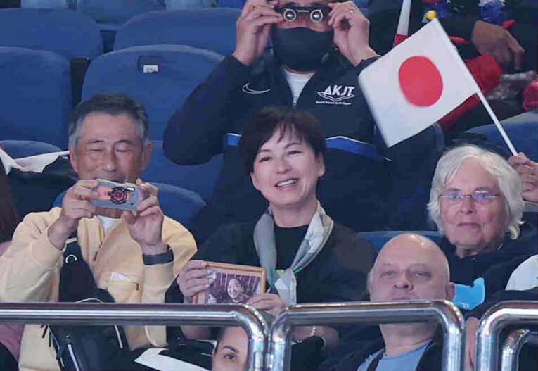 故・仁さんの遺影を手に応援する母の三恵子さん（2022年）©︎JIJI PRESS