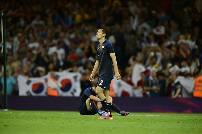 韓国との3位決定戦に敗れ、味方選手が倒れ込む中、ピッチを後にする徳永悠平。 ／ photograph by JMPA