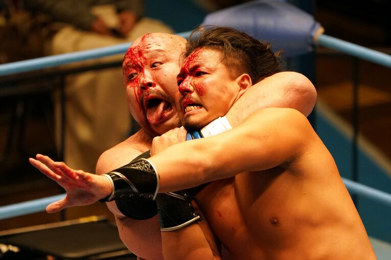 凶器攻撃で出血したジェイク・リーを締め上げる小林